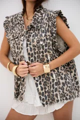 Chaleco de denim con estampado animal print, cuello camisero, cierre frontal con botones metálicos y volados en las sisas.
