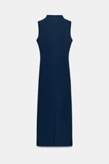 Vestido midi negro con cuello subido y diseño sin mangas (sisa). Presenta un elegante detalle de tejido drapeado en el lateral y cierre trasero con cremallera oculta.