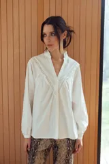 Camisa blanca de mangas largas con cuello mao y volados en el frente.