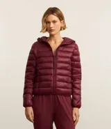 Campera deportiva tipo puffer con capucha, cierre frontal de cremallera y diseño acolchado. Confeccionada en tejido tecnológico ligero, cuenta con mangas largas y capacidad de transformarse en un pequeño bolso.