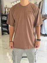 Remera oversize color beige, con diseño estampado en la espalda que incluye tipografía grande y texto descriptivo en negro.