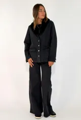 Pantalon de jean negro de corte wide leg, con tiro alto, cierre frontal con botón y bolsillos laterales.