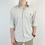 Camisa de manga larga a rayas verticales grises y blancas, con cuello italiano y logo bordado en el pecho.