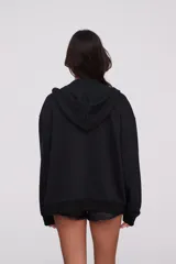Campera canguro de algodón color negro, con capucha, cierre frontal completo y bolsillos delanteros tipo ojal. Diseño de mangas largas y calce holgado.