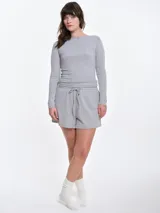 Remera de manga larga entallada en tejido pointelle, con escote bote y detalle de pequeño lazo central. Presenta un acabado con borde picot en el escote.