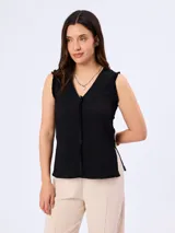 Blusa negra sin mangas, con escote en V y detalles de flecos en los bordes y costuras.