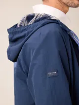 Campera de nylon con cierre frontal, capucha ajustable con cordones y forro interior a cuadros. Presenta bolsillos laterales y logo bordado en el pecho.