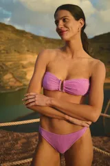 Conjunto de bikini violeta de lycra texturada simil toalla. El corpiño es strapless con tiras ajustables y unión de taza con avío metálico. La bombacha es vedetina con forrería a tono.