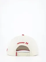 Gorra de béisbol color crema con visera y botón superior rojos. Presenta un logo bordado en el frente con la frase "Sign Your Art" en rojo.