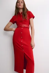 Vestido midi de color rojo, con cuello solapa, manga corta y cierre frontal de botones metálicos. Presenta bolsillos decorativos en el pecho y un cinturón a tono en la cintura.