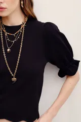Camisa negra de punto con mangas cortas abullonadas y puños con volados.