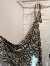 Vestido largo con estampado de hojas en tonos verde y blanco, con escote halter y espalda descubierta.