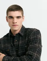 Camisa de franela con diseño a cuadros, cuello button-down, manga larga y botones de madera. Cuenta con dos bolsillos frontales tipo parche con cierre de botón.