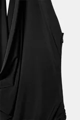 Vestido largo de color negro con cuello halter y detalle de aro metálico en el escote. Presenta un diseño drapeado en la parte frontal y escote en pico pronunciado.