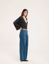 Pantalón de pana color verde oliva, de corte wide leg y largo al tobillo. Tiene cierre delantero con botón, bolsillos laterales y traseros.