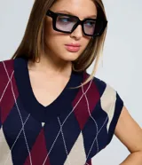 Chaleco de punto de cuello en V sin mangas, con estampado de rombos argyle en tonos azul marino, bordó y beige. Presenta bordes acanalados en el cuello y sisas.