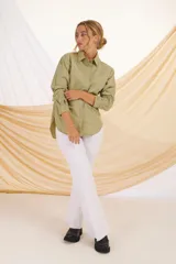 Camisa verde militar de corte holgado, con cuello clásico, cierre frontal con botones, bolsillo de parche en el pecho y mangas largas con puños abotonados.