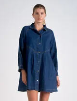 Vestido camisero de denim azul oscuro, marca Elan. Tiene cuello con solapa, abertura central con botones metálicos dorados, bolsillos laterales, mangas largas con puño elastizado, largo mini y calce holgado.