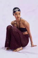 Pantalón largo acampanado de punto calado color vino, con cintura elástica.