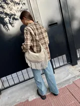 Cartera tipo hobo de cuero color arena, con diseño de media luna y flecos largos en la parte inferior. Cuenta con correa ajustable para llevar al hombro y cierre superior.