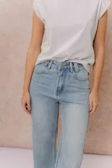 Jean wide leg de tiro medio-alto en denim azul medio con lavado desgastado. Presenta diseño de cinco bolsillos, cierre con botón y cremallera, y pierna amplia de caída recta.