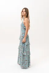 Vestido largo celeste con estampado abstracto en tonos marrones, escote halter con abertura en el frente y volados escalonados en la falda.