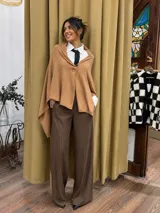 Pashmina de tejido suave con diseño abierto y cierre frontal mediante un botón central, ideal para usar como capa sobre otras prendas.