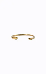 Pulsera rígida de metal dorado con diseño circular abierto y acabado pulido. Presenta una estructura lisa con extremos redondeados y ligeramente cónicos.