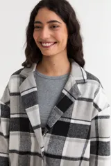 Tapado liviano de paño con diseño de cuadros en tonos gris, blanco y negro. Presenta cuello solapa, cierre frontal con botones y bolsillos laterales.