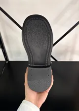 Botas de caña media color negro, con suela track y correas con hebilla plateada alrededor de la caña. El material es símil cuero.