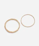 Kit de dos brazaletes rígidos estilo bangle de metal dorado, compuestos por uno con textura y acabado martillado y otro fino de diseño liso.