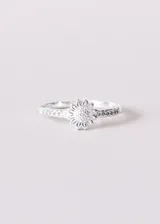 Anillo plateado con forma de flor central y zirconias laterales. Enchapado en plata 925.