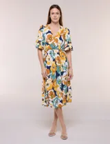 Vestido midi de calce holgado y caída fluida con escote en V cruzado, cintura elastizada fruncida y mangas cortas con volados superpuestos. Cuenta con un diseño estampado de flores grandes en tonos amarillo, blanco, azul marino y verde.