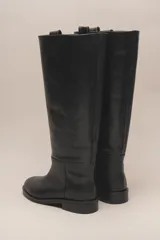 Bota de caña alta color marrón, confeccionada en cuero vacuno con forro y plantilla de cuero. Tiene suela de goma negra y un diseño de caña ancha.