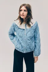 Campera acolchada ligera de denim en mezcla de algodón y lyocell, modelo Divided de H&M. Presenta cuello redondo, cierre frontal con botones a presión, hombros ligeramente caídos, mangas abullonadas y elástico revestido en los puños y el dobladillo inferior. Diseño pespunteado con ondas.