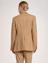 Blazer de mujer color beige, confeccionado en material similar a la gamuza, con solapas anchas, un botón forrado en la parte frontal y bolsillos de ojal.