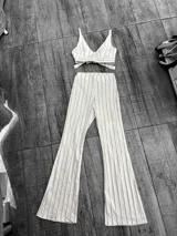 Conjunto de dos piezas compuesto por un top corto con escote en V y tirantes finos, y un pantalón de corte oxford con diseño de rayas verticales finas en color marrón sobre fondo blanco.