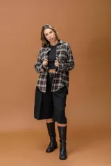 Camisa de corte oversize con diseño a cuadros en tonos marrones, grises y blancos. Presenta cuello clásico, cierre frontal con botones y mangas largas.