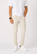 Jean skinny color beige, de corte ajustado y tiro medio, con bolsillos clásicos y cierre frontal.