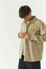 Sobrecamisa de pana color beige, con cuello clásico, cierre frontal de botones y bolsillos tipo cartera en el pecho.