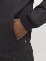 Campera bomber negra de tejido liviano de lino y algodón, con cuello tipo baseball, cierre con cremallera, mangas largas con puños de canalé y bolsillos delanteros.