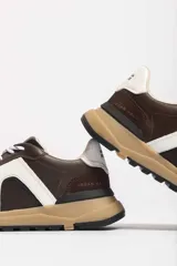 Zapatillas deportivas marrones con detalles en blanco y suela color caramelo.