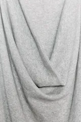 Top gris de escote drapeado, con una manga sisa y una manga corta. Presenta frunces laterales y un bajo asimétrico.