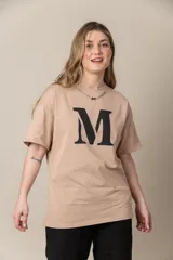 Remera gris con estampa de la letra M en negro y cadena plateada en el cuello.