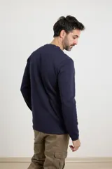 Remera de manga larga en tejido elastizado, color azul, con cuello tipo camisa, cartera con botones y detalles en eco gamuza en la base del cuello y la cartera.
