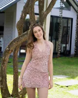 Vestido corto color fucsia con escote en V, breteles finos que se atan al cuello, corte a la altura de la cadera y falda acampanada con ruedo irregular.