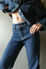 Pantalón de jean azul oscuro, de corte recto y tiro medio, con detalle de ruedo desflecado.