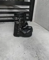 Botas negras de ecocuero con plataforma y detalles de hebillas y cierres.