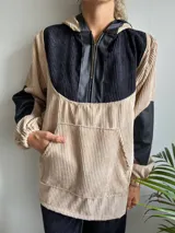 Canguro de pana color beige con capucha, mangas largas de cuero sintético negro y cierre frontal parcial con cremallera.