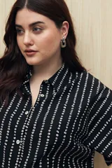 Conjunto de camisa y pantalón a rayas verticales en blanco y negro. La camisa es de manga corta, confeccionada en viscosa suave y fluida, con cuello clásico y botones al frente. El pantalón es de corte palazzo, con cintura alta y pernera ancha.